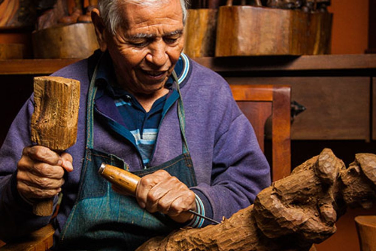 Artista Ditinho Joana fazendo uma escultura em madeira