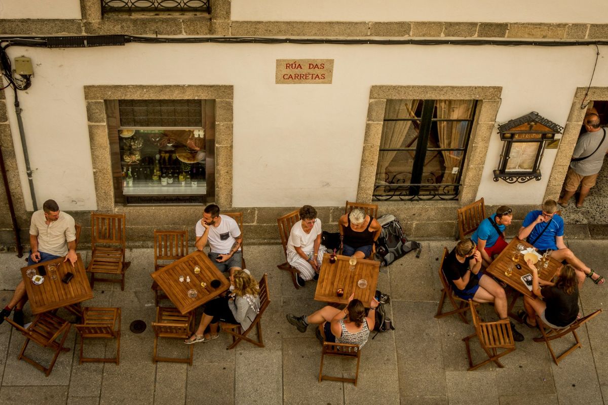 Pessoas sentadas em mesas de bar em Santiago de Compostela