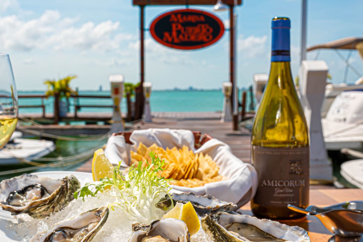 Mesa com prato de ostras e vinho com vista para o mar